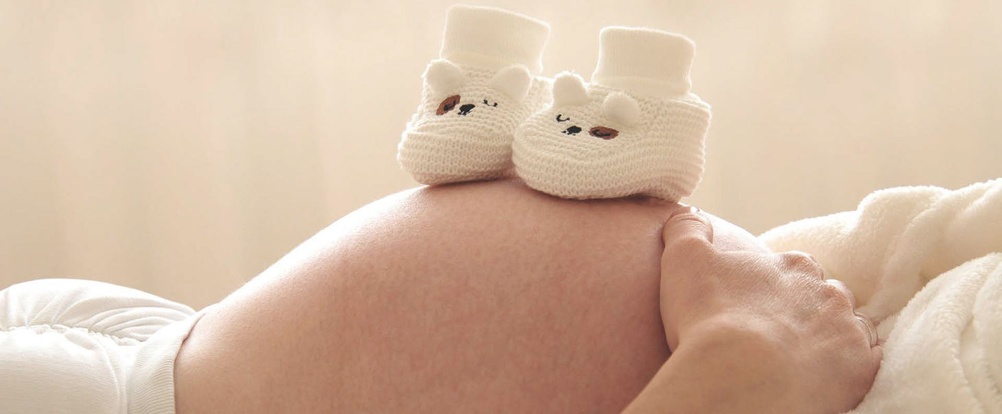 Babybauch mit Babyschuhen drauf