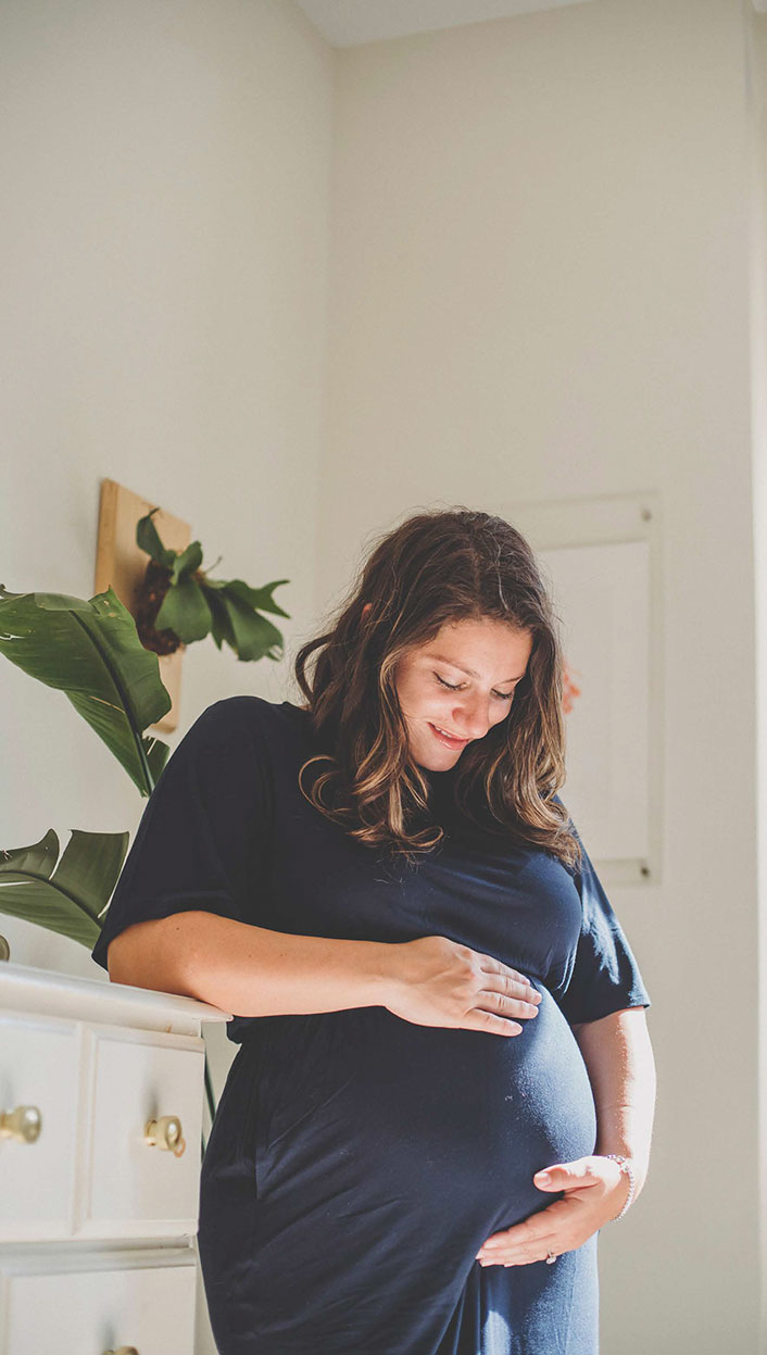 Schwangere Frau betrachtet Babybauch